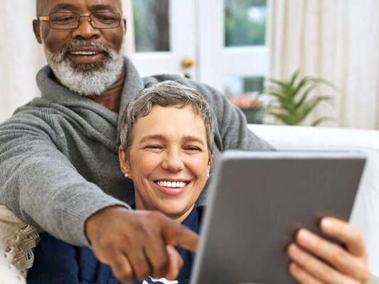 Older couple smiling while using iPad