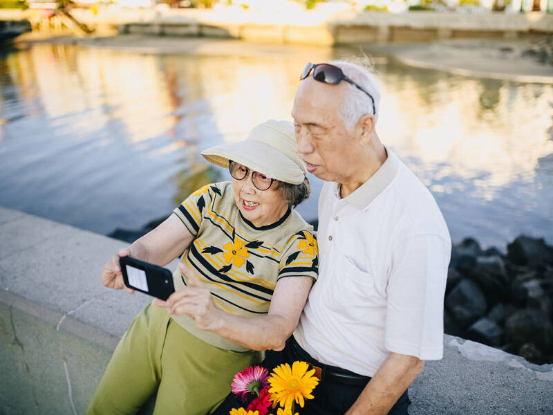 Older couple taking selfie near a pond