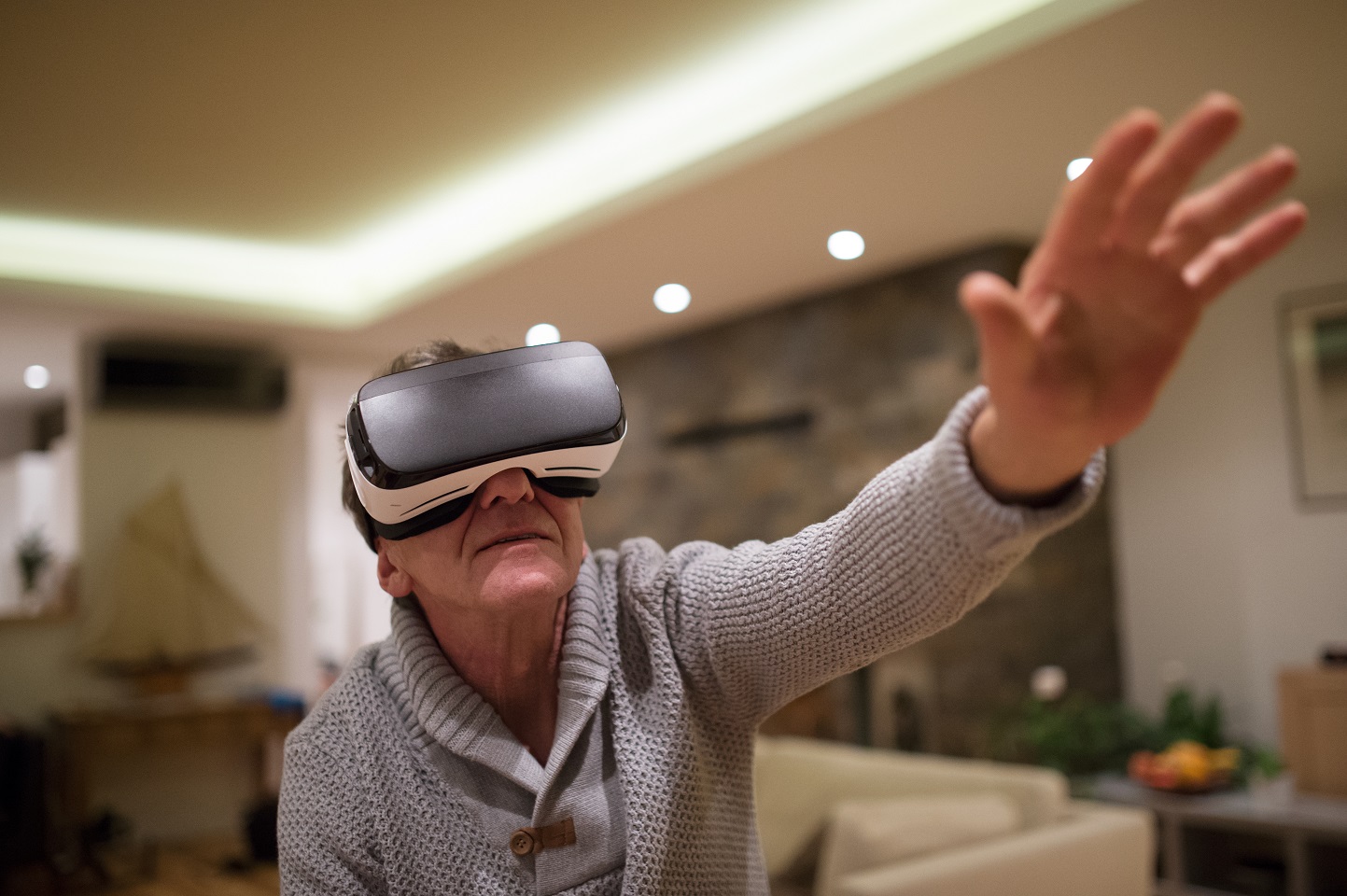 Senior man wearing virtual reality goggles at home